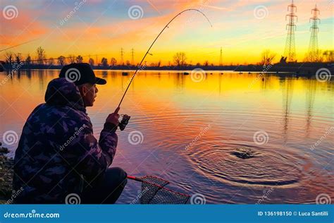 Fisherman At Sunset Who Is Catching A Fish Stock Photo Image Of