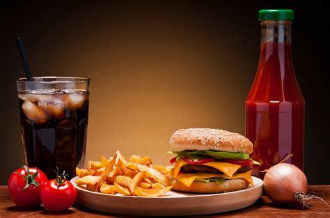 Burger With Fries On Plate Beside Soda On Drinking Glass And Ketchup