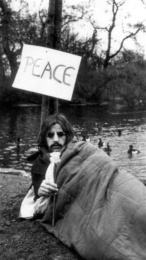 A Man Holding A Sign That Says Peace In Front Of Some Ducks On The Water