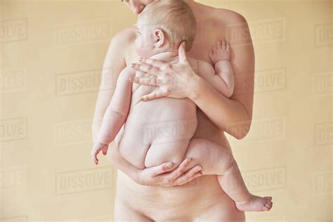 Naked Mother Comforting Naked Baby Resting Against Her Chest Stock