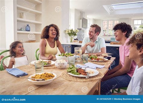 Familia Sentada Alrededor De La Mesa Comiendo Juntos En Casa Imagen De