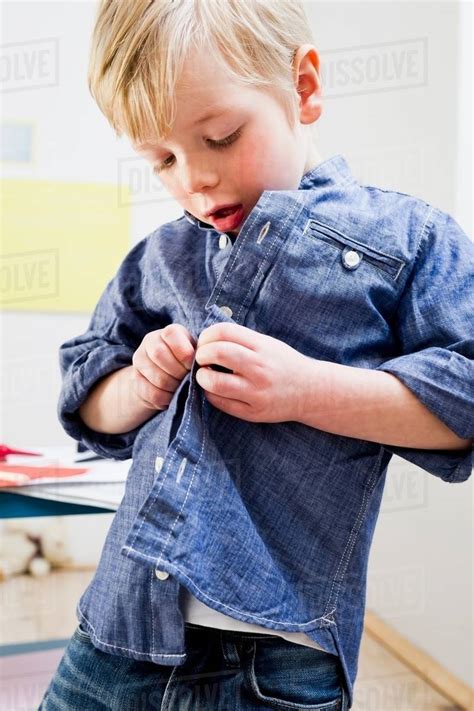 Boy Buttoning Shirt At Home Stock Photo Dissolve