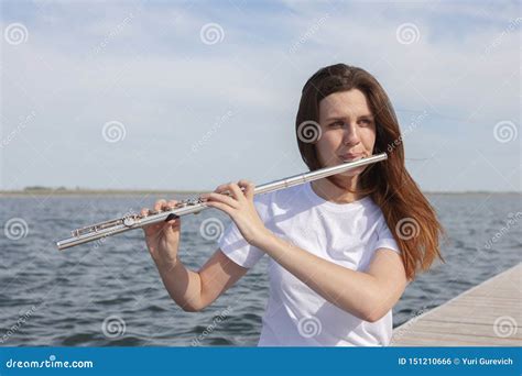 A Beautiful Woman Posing In Beach While Playing On A Flute Stock Photo