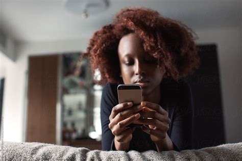 Young Black Woman Lying On Bed And Using Smartphone By Visualspectrum