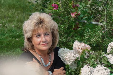 60 Year Old Woman In The Garden A Mature Woman Enjoys The Flowers Of A