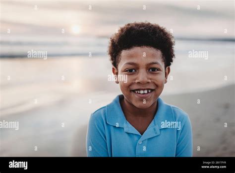 Portrait Of Young School Aged Boy Smiling At Beach During Sunset Stock
