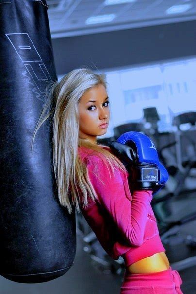 Фото Блондинка в розовом спортивном костюме стоит рядом с боксерской грушей в боксерских перчатках