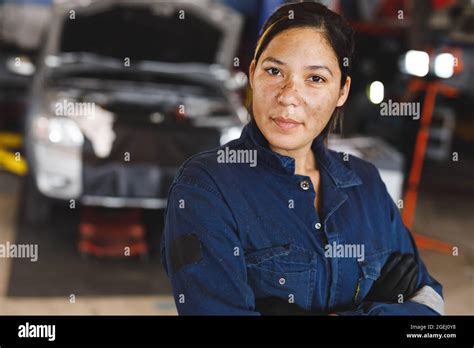 Mixed Race Female Car Mechanic Wearing Overalls Looking At Camera