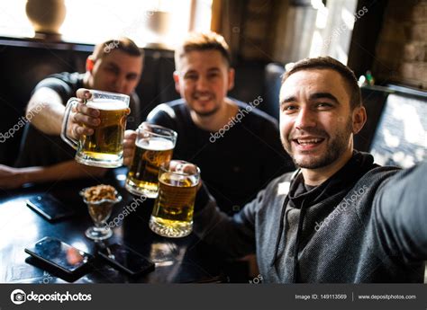 Happy Male Friends Drinking Beer And Taking Selfie With Smartphone At