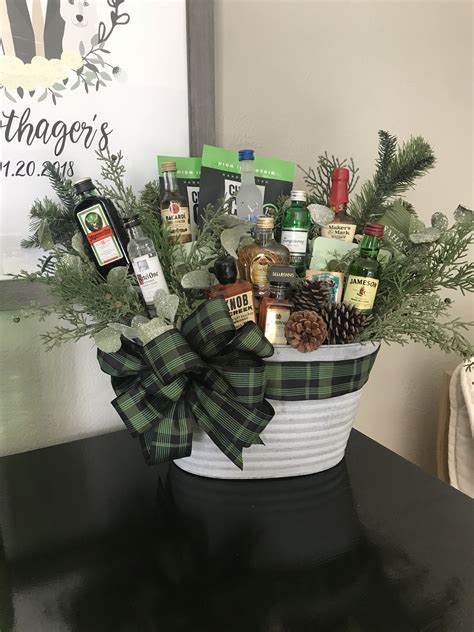 A Basket Filled With Liquor Bottles And Pine Cones On Top Of A Table