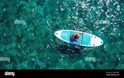 Top Down View Picture Of A Woman Paddling On Her Knees On The Sup Board