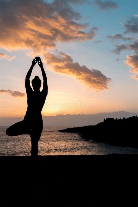 Toma Vertical De Una Mujer Haciendo Yoga En La Playa Durante La Puesta