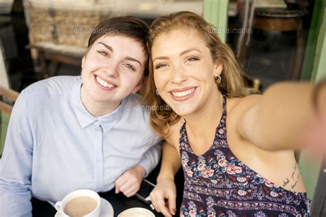 A Young Lesbian Couple Take A Selfie Outside A Coffee Shop 11082002520 の写真素材・イラスト素材｜アマナイメージズ