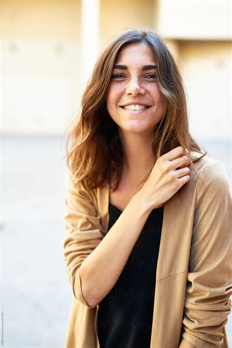 view smiling woman in beige jacket looking at camera by stocksy contributor guille faingold