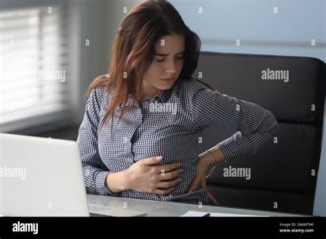 Young Female Employee Suffer From Lower Backache In Office Stock Photo