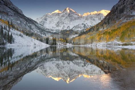 Reflections Of Snow Covered Mountains And Golden Aspen Trees In A Lake