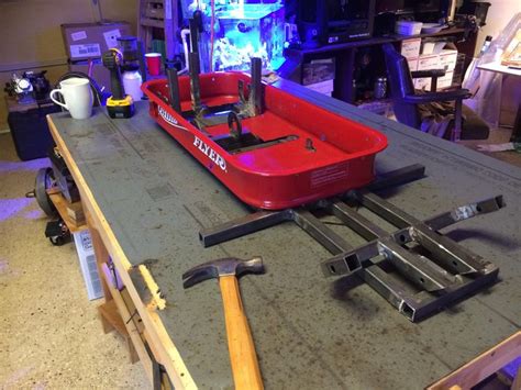 A Red Boat Sitting On Top Of A Wooden Table Next To A Cup And Wrenches