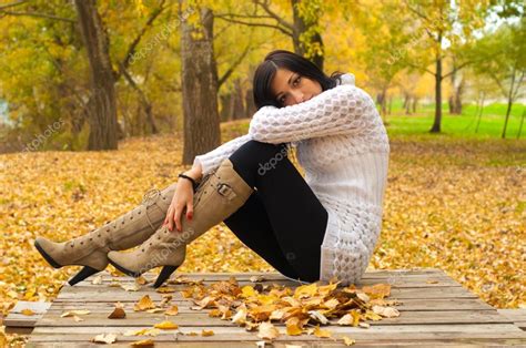 Beautiful Lady Sitting On The Table In The Park On Cloudy Autumn Day