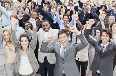 Portrait Of Business People Cheering With Arms Raised In Crowd Stock Photo
