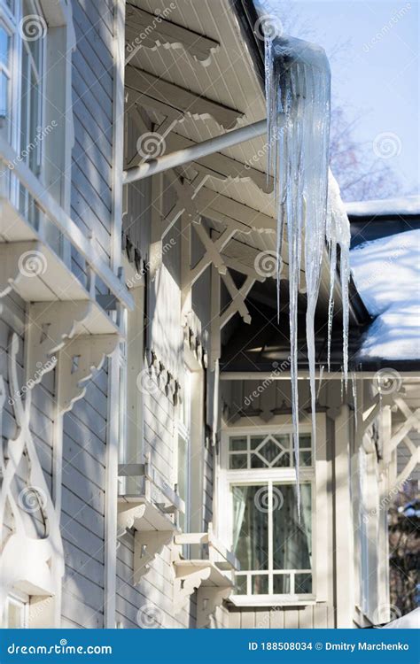 Icicles Hanging From The Roof Of A Wooden Building In Winter In Sunny
