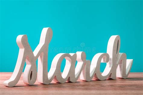 March Wooden Carved Word At Turquoise Background Beginning Of March