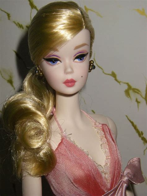 A Barbie Doll With Long Blonde Hair And Blue Eyes Wearing A Pink Evening Dress
