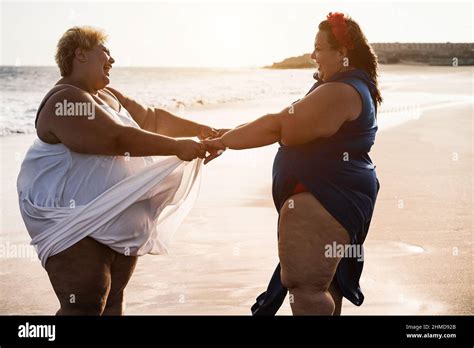 Curvy Women Dancing On The Beach Having Fun During Summer Vacation Focus On Faces Stock Photo