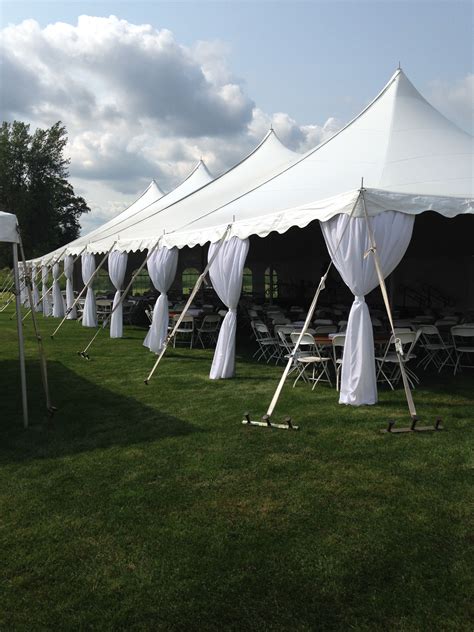 Several White Tents Set Up In The Grass With Drapes On Each Side And