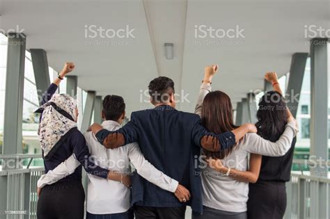 Rear View Of Unrecognizable Business Team With Arms Around One Another