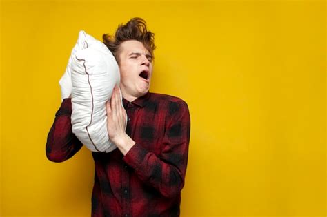 Premium Photo Sleepy Tired Guy Yawns And Holds A Pillow On Yellow