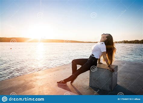 Woman Sitting On Pier Against Water And Sunset Stock Photo Image Of Horizon Dress