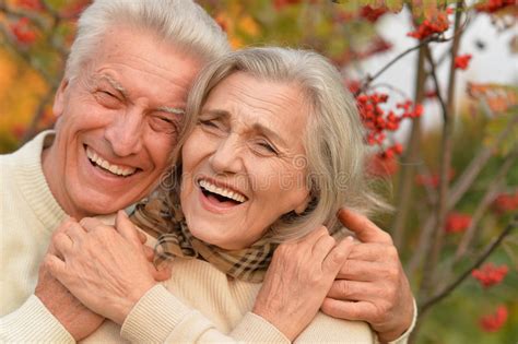 Portrait Of A Middle Aged Couple Laughing In Autumn Park Stock Photo