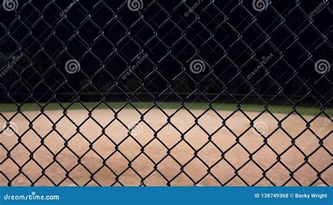 Looking At A Baseball Field At Night Through The Fence Stock Photo