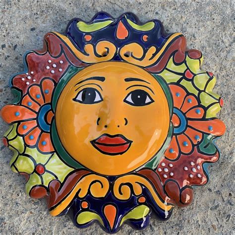 A Ceramic Sun Face Sitting On The Ground