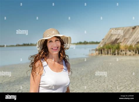 Attractive Mature Busty Woman In Very Good Shape With Wide Hat On A Sun Split Beach With Straw