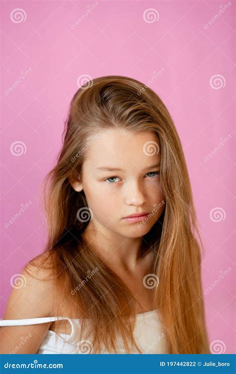 Portrait Of A Gentle 9 Year Old Long Haired Girl In A Light T Shirt Against A Lilac Wall Stock