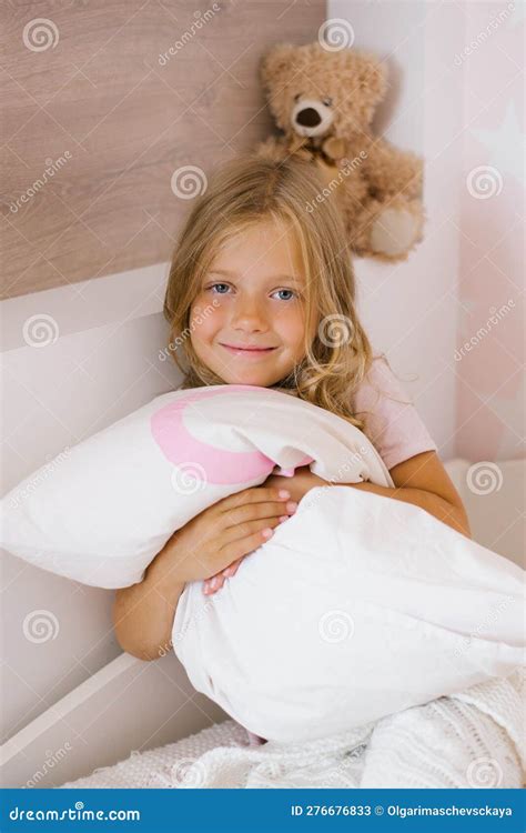 Cute Long Haired Girl Is Sitting On The Bed And Hugging A Pillow Stock