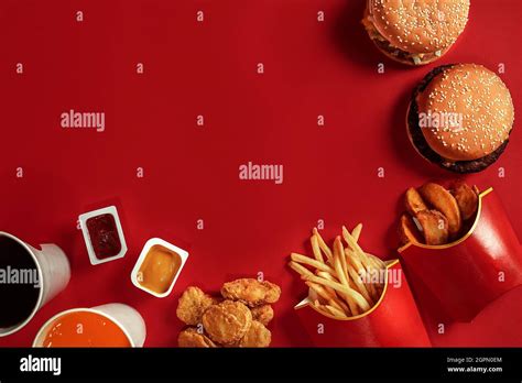 Two Hamburgers And French Fries Sauces And Drinks On Red Background