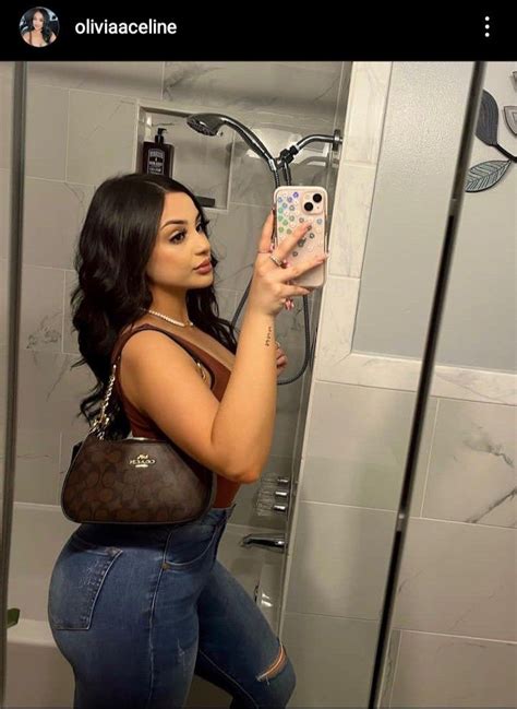 A Woman Is Taking A Selfie In The Bathroom With Her Cell Phone And Purse