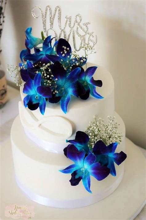A Three Tiered Cake With Blue Flowers On Top