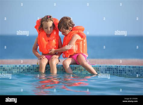 Zwei Kleine Mädchen In Schwimmwesten Sitzen Auf Sims Pool Resort Stockfotografie Alamy