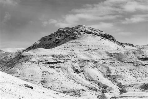 Black And White Winter Landscape Of A Steep Rocky Hill Covered With