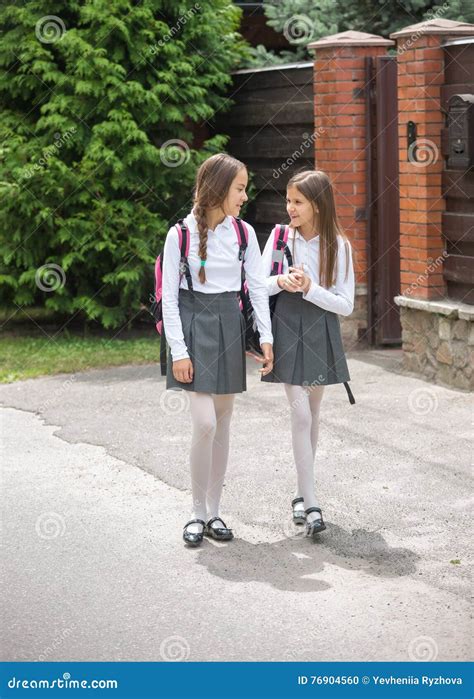 Cute Girls In Uniform Walking To School And Chatting Stock Photo