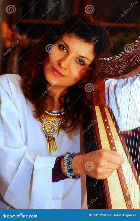 Young Woman Playing Celtic Harp In A White Angelic Historical Costume