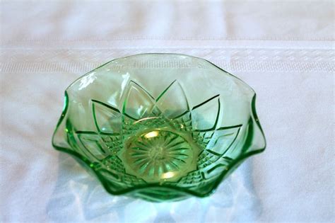 A Green Glass Bowl Sitting On Top Of A White Tablecloth Covered Table