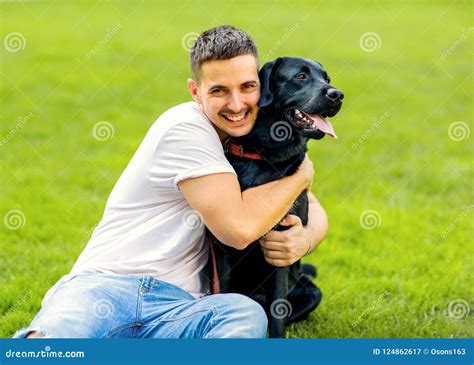 Guy Hugging With His Dog Labrador Playing In The Park Stock Image
