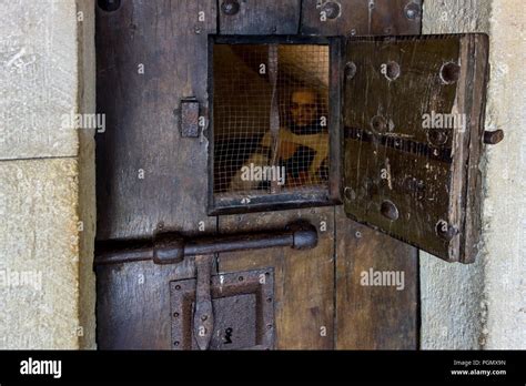 Heavy Wooden Medieval Prison Cell Door With Open Hatch Showing Prisoner
