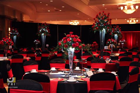 A Banquet Room Set Up With Black And Red Linens Flowers And Centerpieces