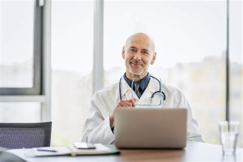 Male Doctor Using Cellphone And Laptop While Working In Doctor`s Room