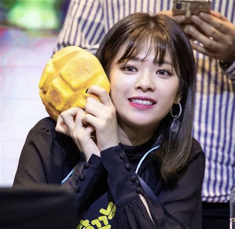 A Woman Holding A Piece Of Food In Her Hand And Smiling At The Camera While Another Person Looks On
